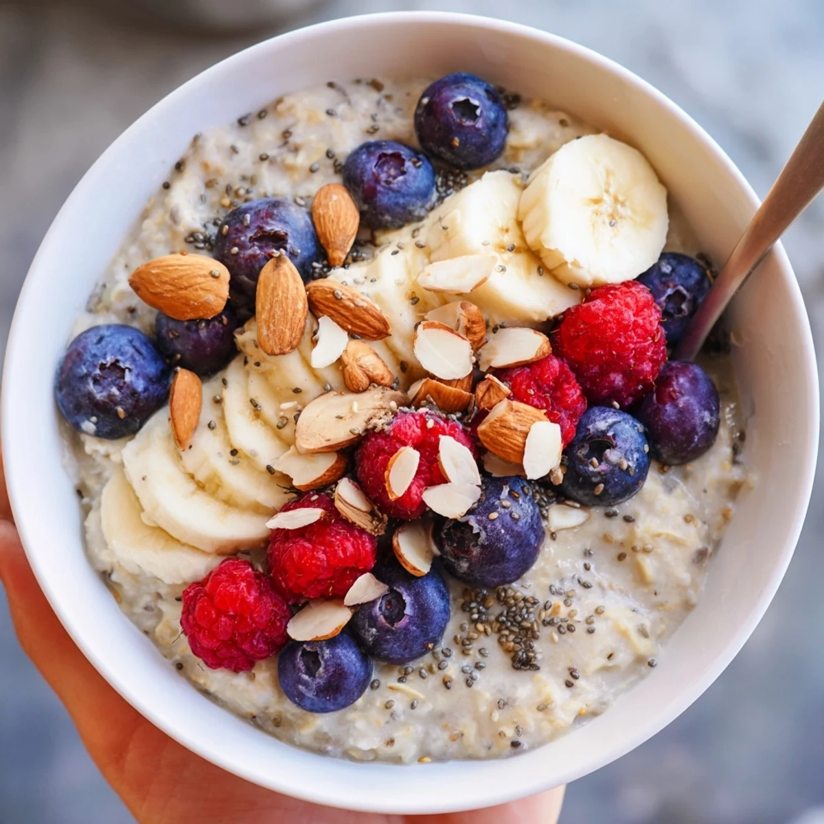 Close-up of a nutritious Creamy Breakfast Oats bowl featuring ripe banana slices and pecans, ready to enjoy with a wooden spoon.