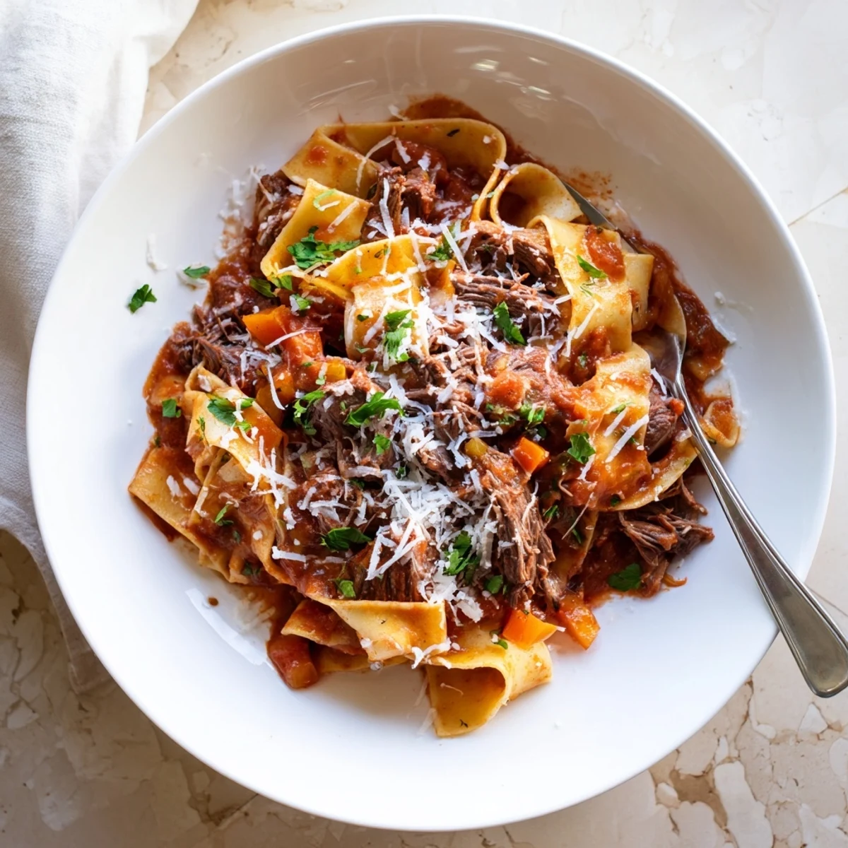 Hearty Italian slow cooker beef ragu served on wide pappardelle noodles, topped with grated Parmesan and fresh herbs for dinner.  