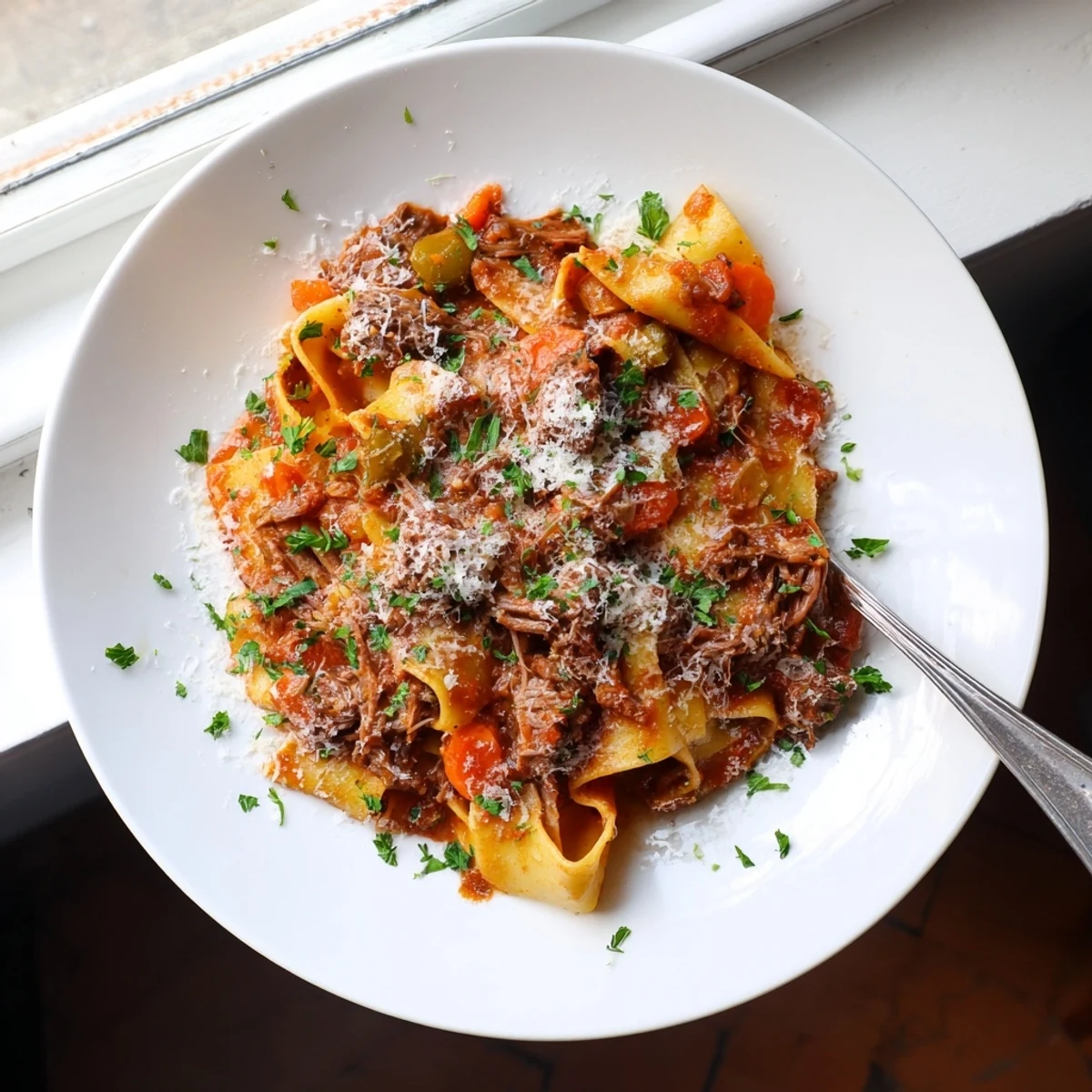 Tender beef chuck roast slow-cooked in red wine tomato sauce, tossed with silky pappardelle pasta and fresh Italian parsley garnish.