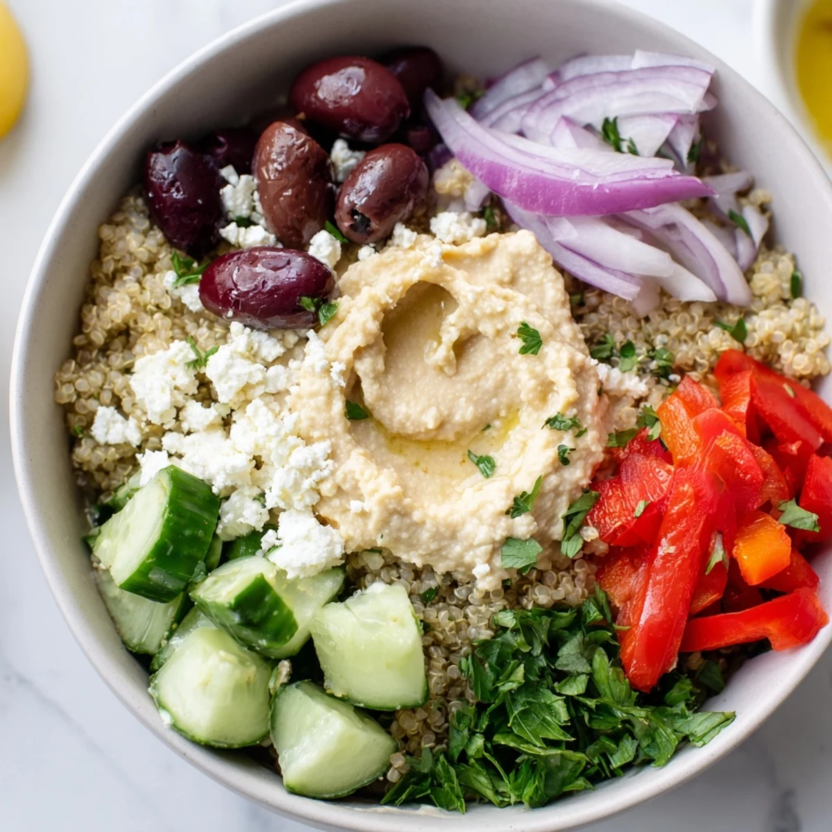 Serving of Mediterranean Quinoa Bowl with Hummus, garnished with parsley and a lemony olive oil drizzle.  