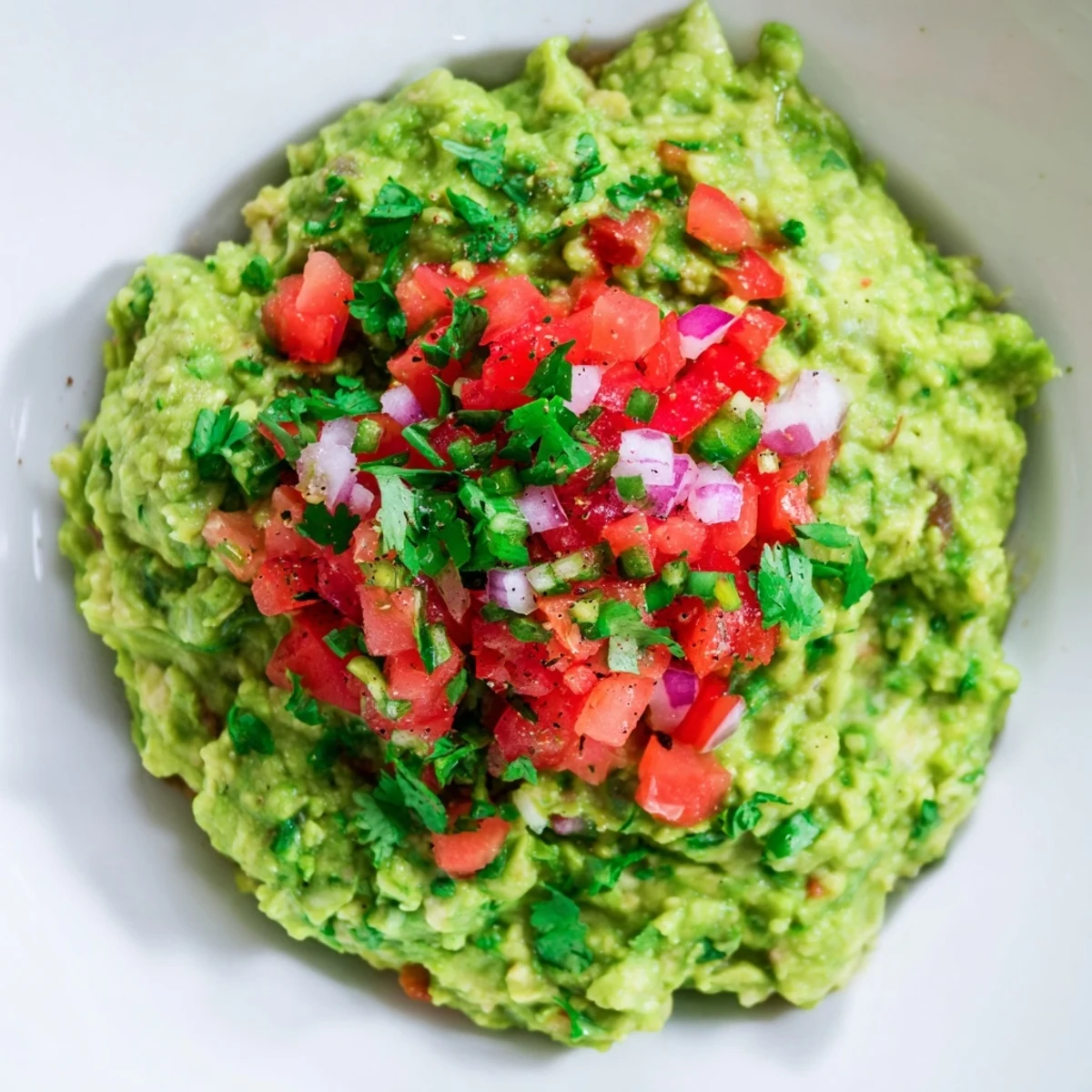 Mashed avocado mounds in a rustic bowl, layered with zesty Pico de Gallo, ready for dipping with crispy tortilla chips.