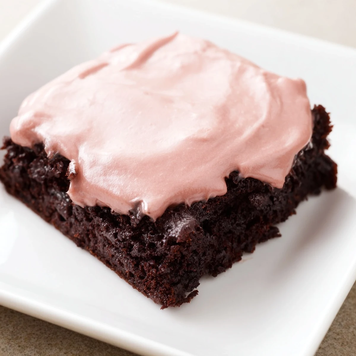 A batch of homemade Brownies with Pink Frosting, glistening with vibrant pink buttercream on top.