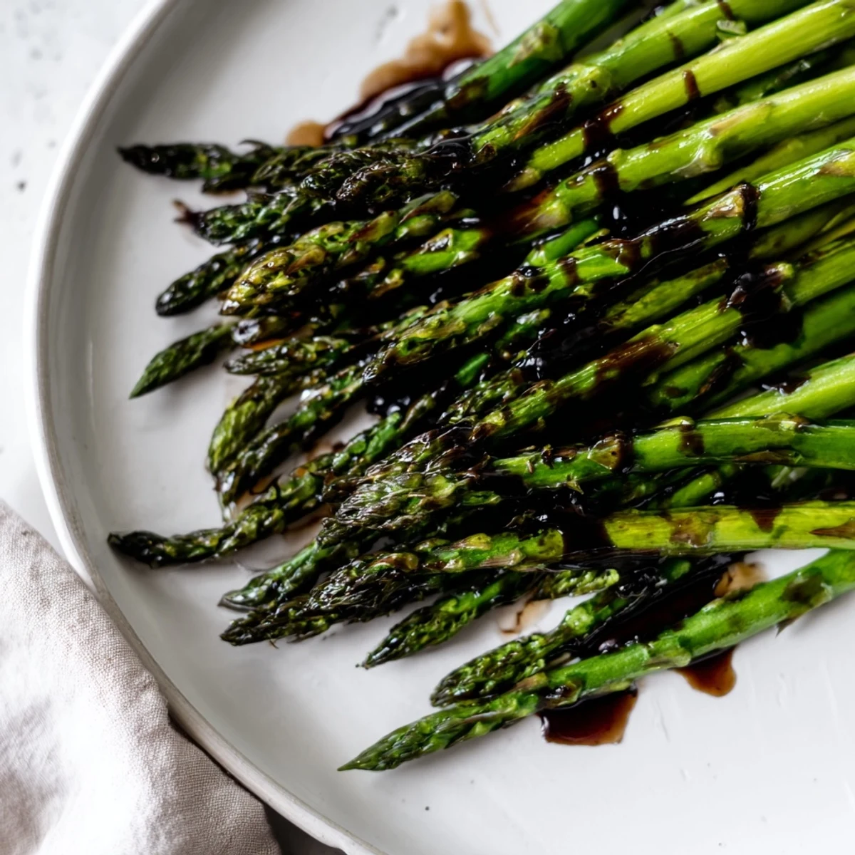 Golden roasted asparagus with balsamic glaze, served warm from the oven on a rustic platter.