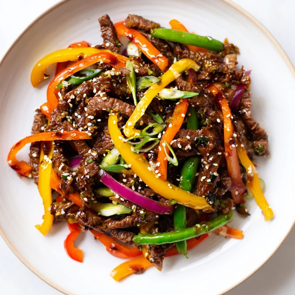 A close-up view shows juicy beef and crunchy veggies coated in a bold, spicy glaze, garnished with sesame seeds and green onions.