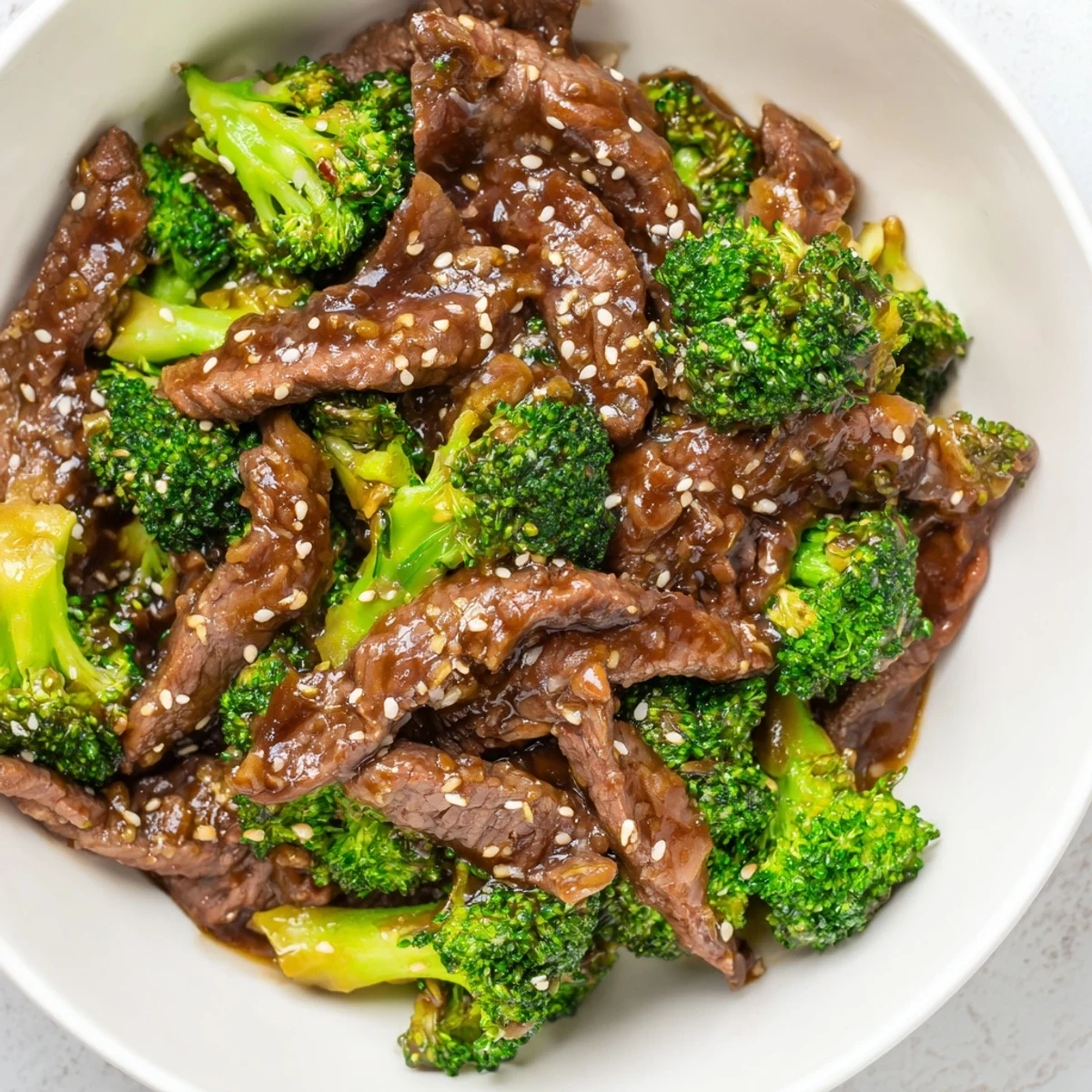 Sizzling Beef and Broccoli with Soy Sauce Glaze in a skillet, garnished with sesame seeds and green onions for extra flavor.