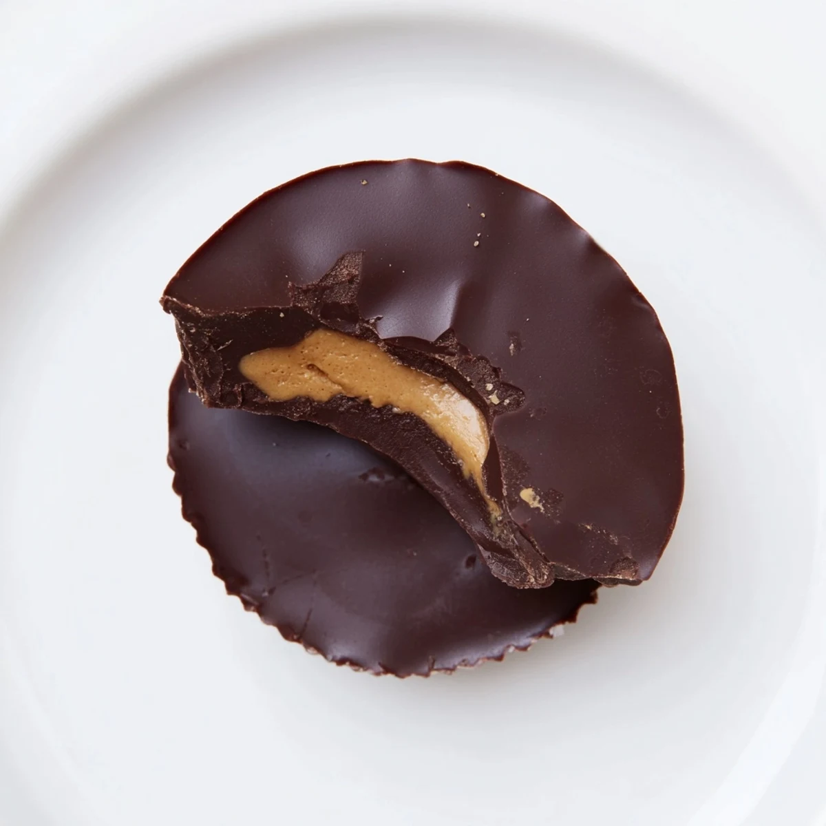 On a marble countertop, twelve Chocolate Peanut Butter Cups display smooth chocolate tops and a dusting of flaky sea salt.