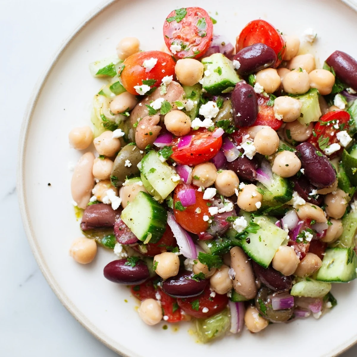 Overhead shot of Mediterranean Dense Bean Salad topped with crumbled feta and Kalamata olives, ideal for a vibrant gluten-free and vegetarian lunch.
