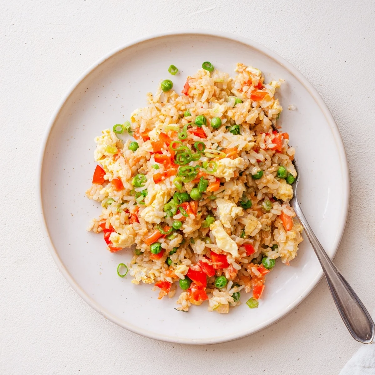A wok filled with golden Bang Bang Fried Rice shows fluffy grains, scrambled eggs, and a bright lime wedge garnish.