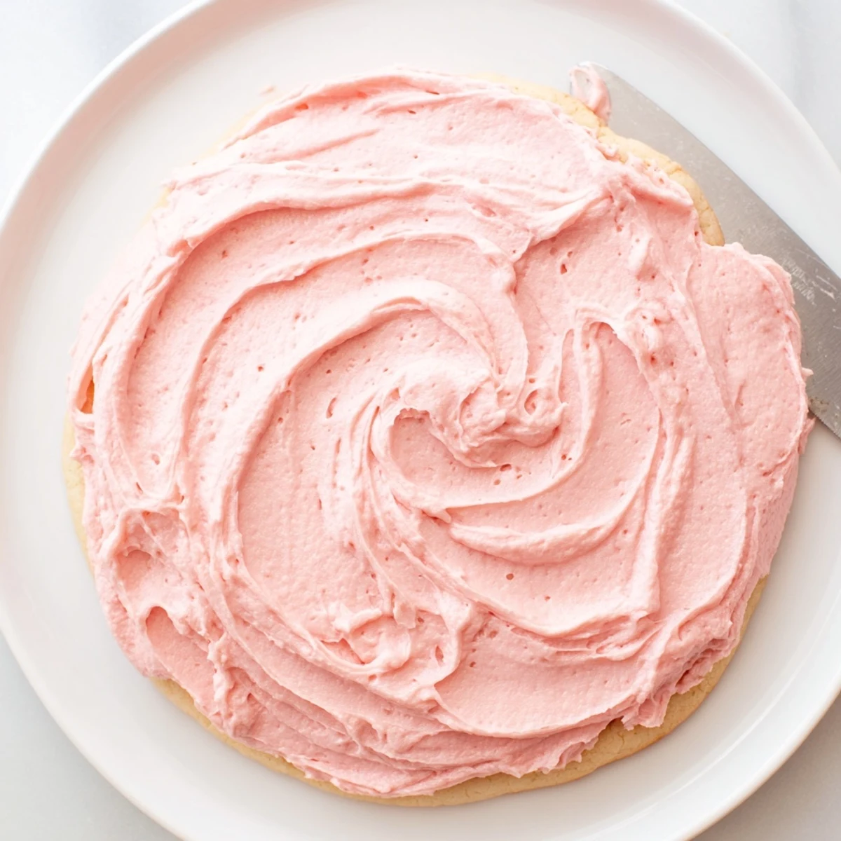 Plate of Giant Chilled Crumbl Sugar Cookies with creamy pink frosting, stacked and dusted with powdered sugar for a bakery look.