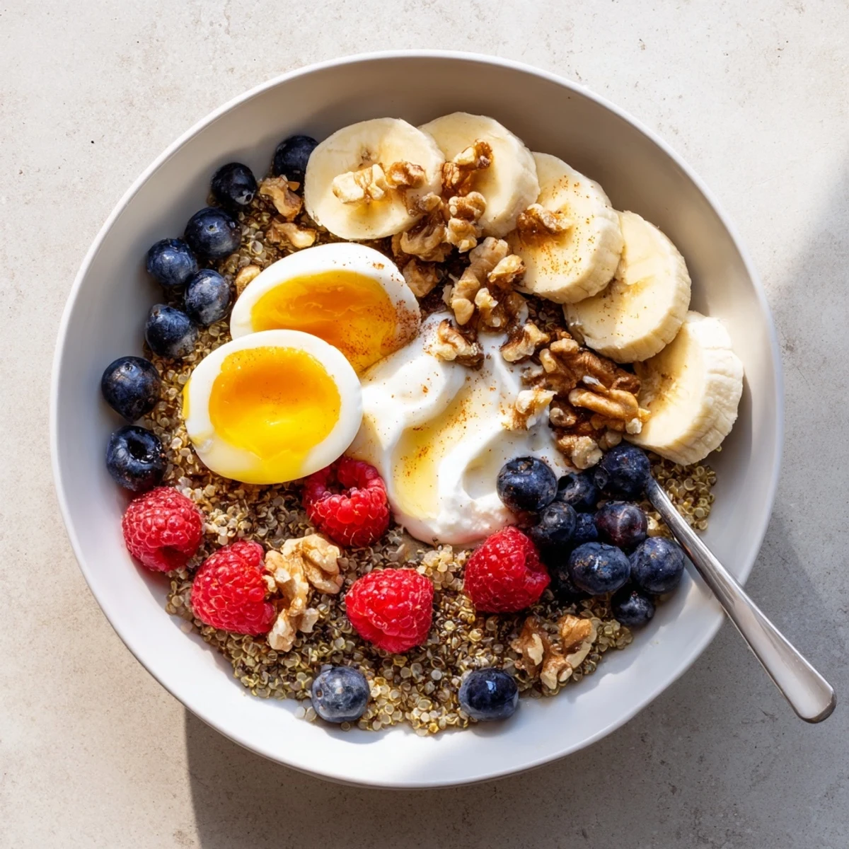 Soft-boiled eggs and Greek yogurt crown a colorful Dietitians Balanced Breakfast Bowl with quinoa and fresh berries.