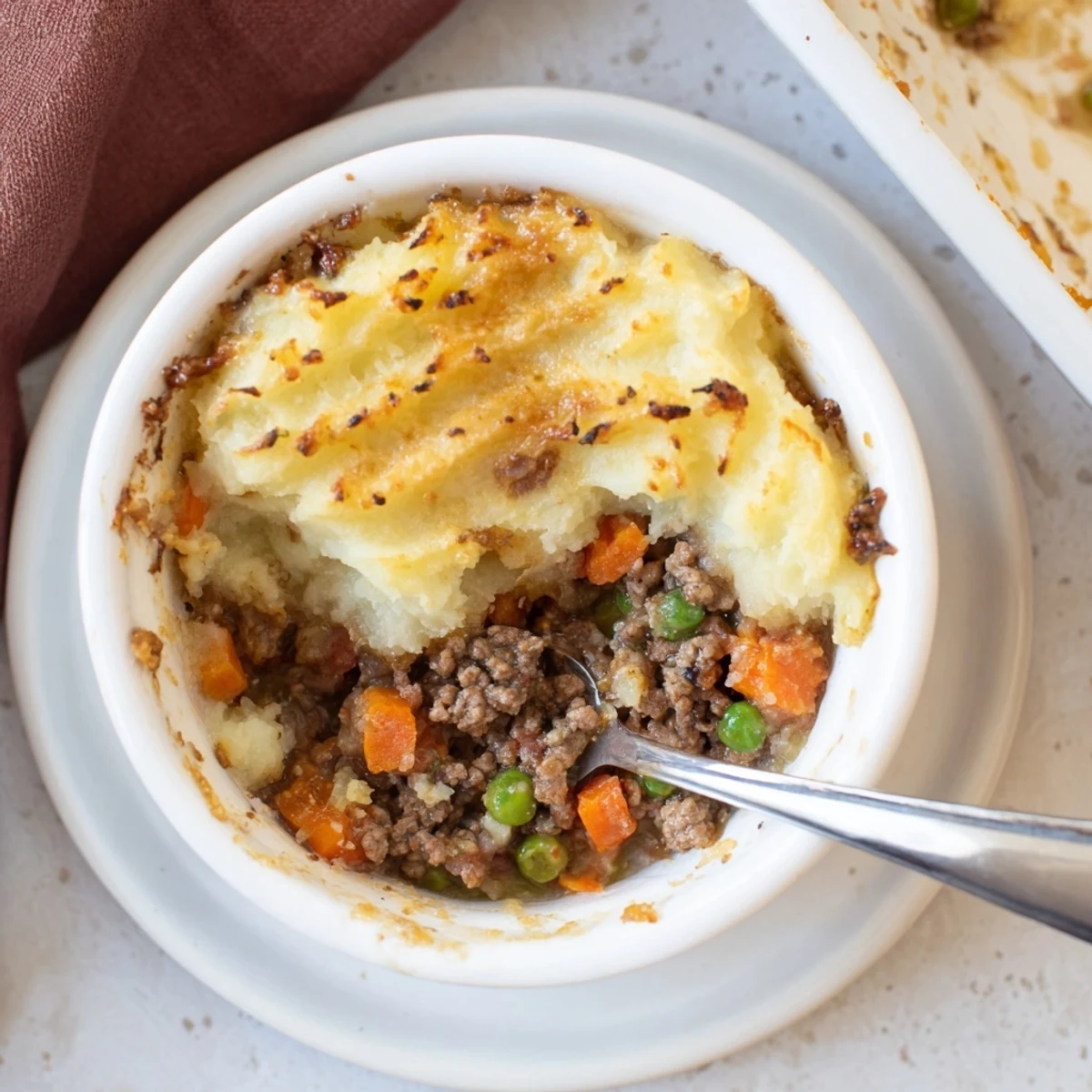 Mini Shepherd's Pie served in individual portions, bubbling filling and cheesy crust on a wooden table.
