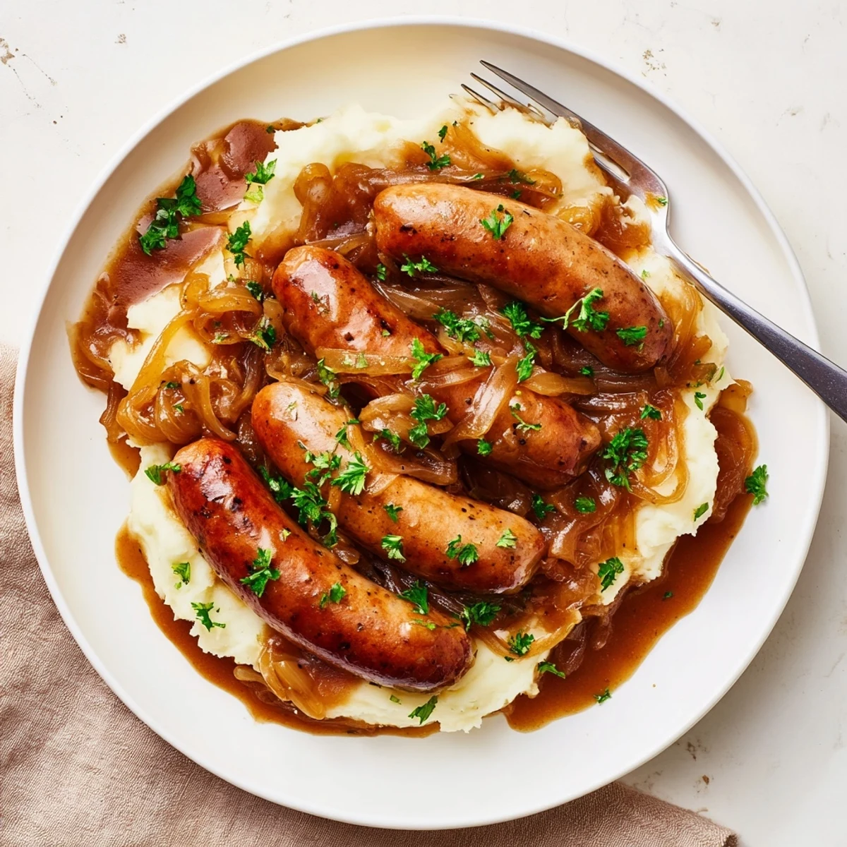 Golden brown sausages in a rich Sausages in Onion Gravy, perfect for a hearty British dinner recipe.