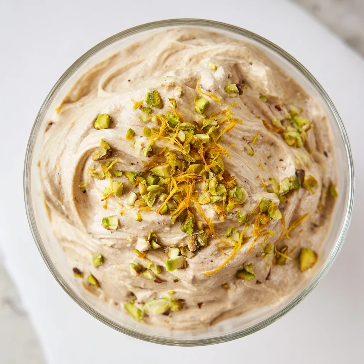 Light fluffy Lebanese date orange blossom mousse speckled with orange zest and crushed nuts in individual serving bowls