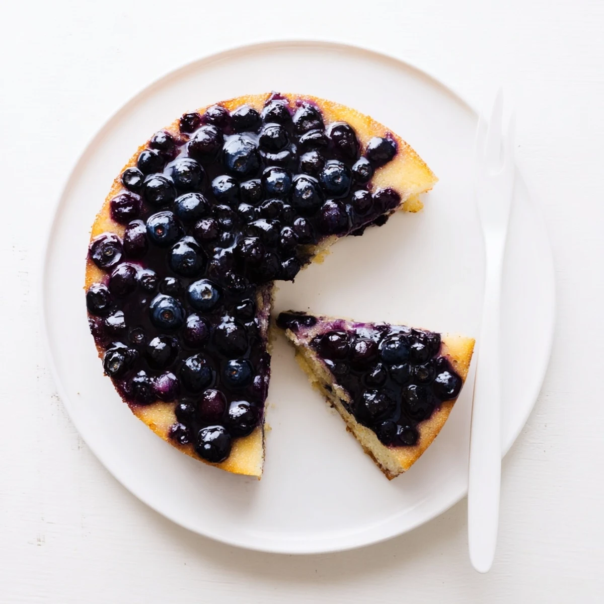 Moist blueberry upside down cake inverted onto serving plate with glistening berry layer