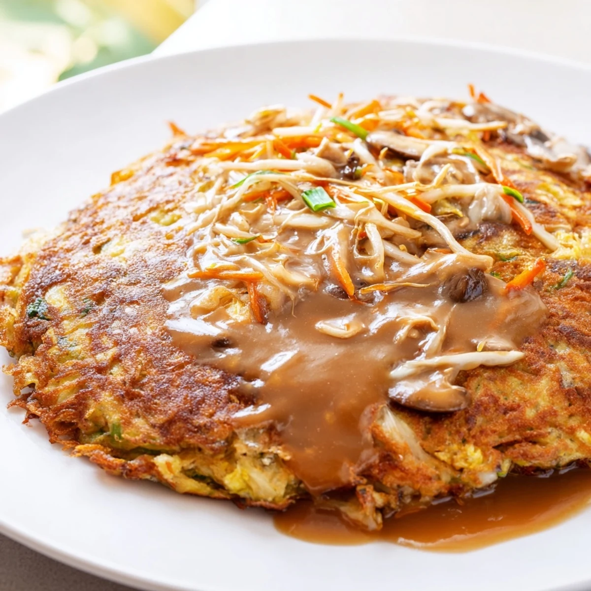 Crispy fried Egg Foo Young drizzled with savory brown gravy over a white plate