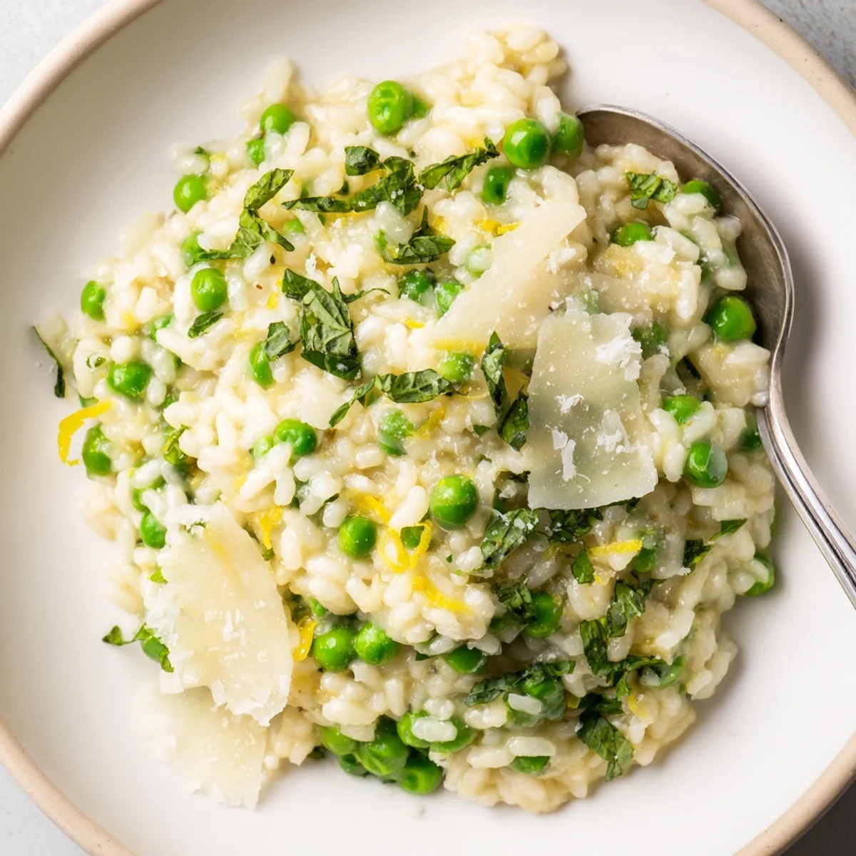 Golden Arborio rice simmered with sweet spring peas and mint, garnished with lemon zest and extra cheese on top