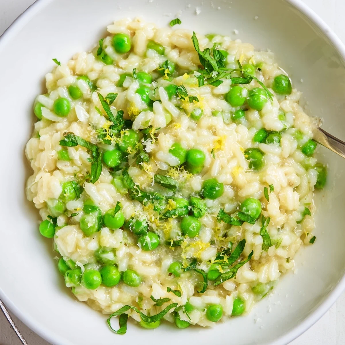 Close-up of vegetarian spring pea risotto showing creamy texture and bright green peas scattered throughout the rice