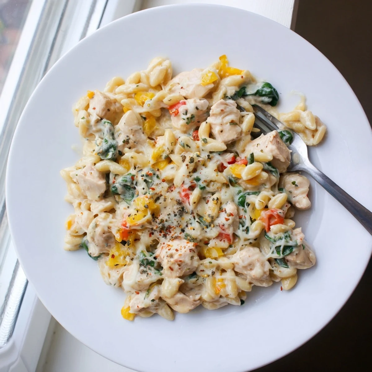 Savory chicken and orzo pasta dish bubbling with melted cheese in skillet