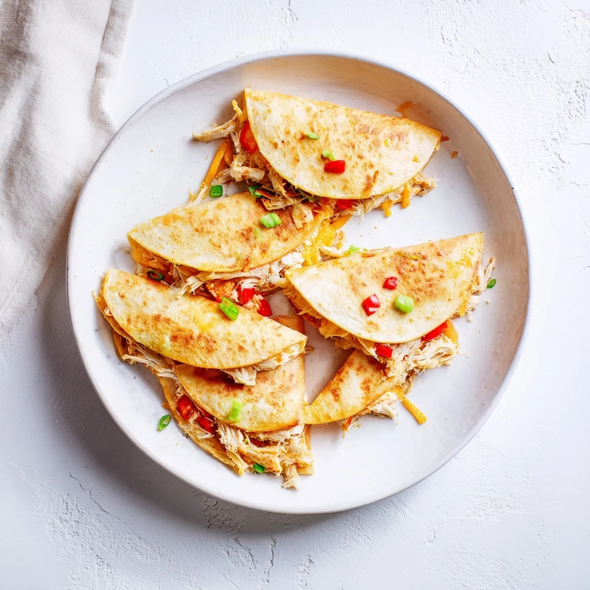 Golden brown baked chicken and cheese quesadillas cut into wedges on a white plate