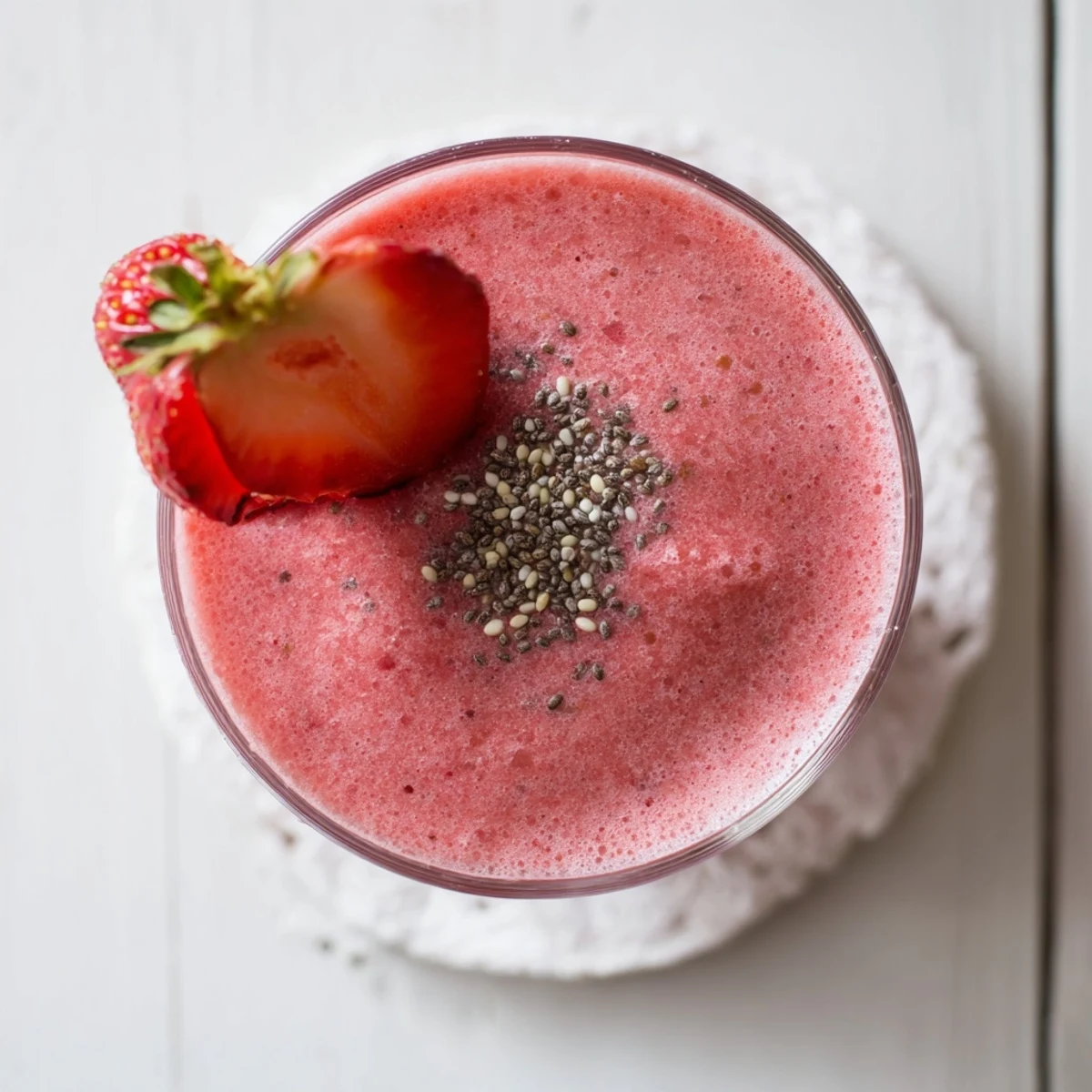 Creamy pink Greek yogurt strawberry smoothie garnished with whole strawberry on glass rim