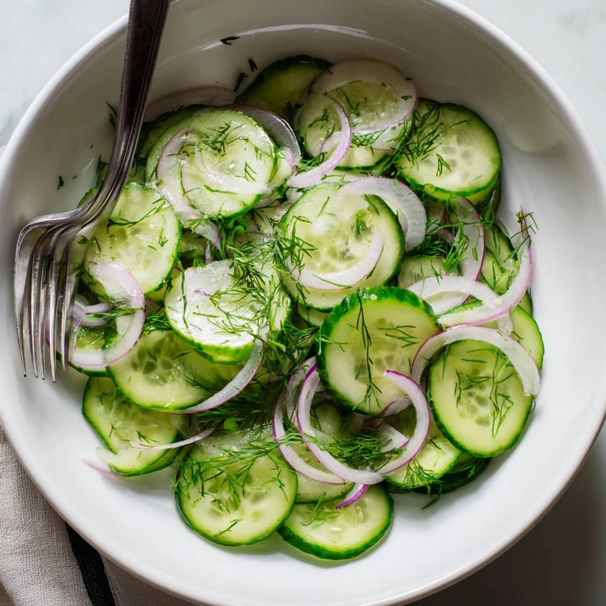 Crisp cucumber salad tossed with red onion, fresh dill, and tangy vinegar dressing for a refreshing summer side