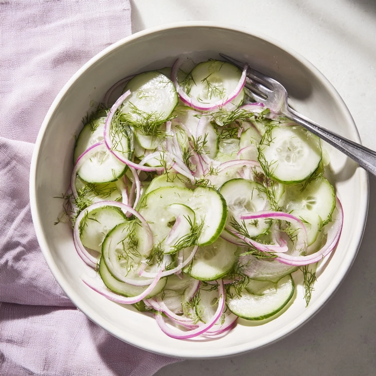 Easy refreshing cucumber salad with vibrant red onion and chopped dill drizzled with sweet tangy dressing