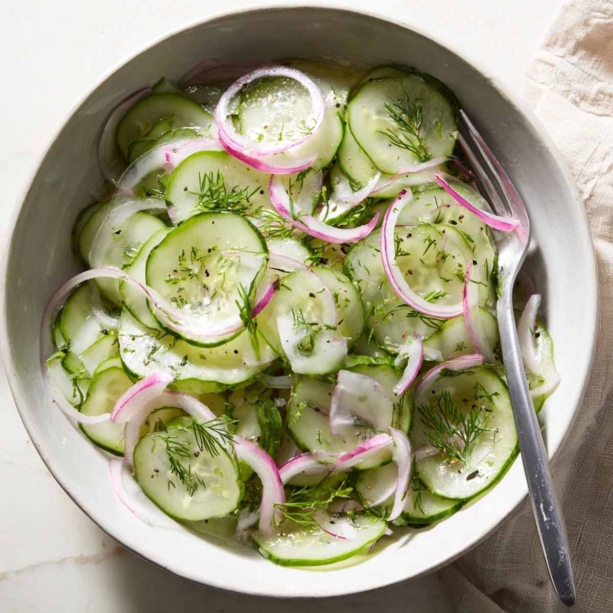 Fresh cucumber salad featuring thinly sliced vegetables in a light olive oil and rice vinegar dressing, perfect for picnics