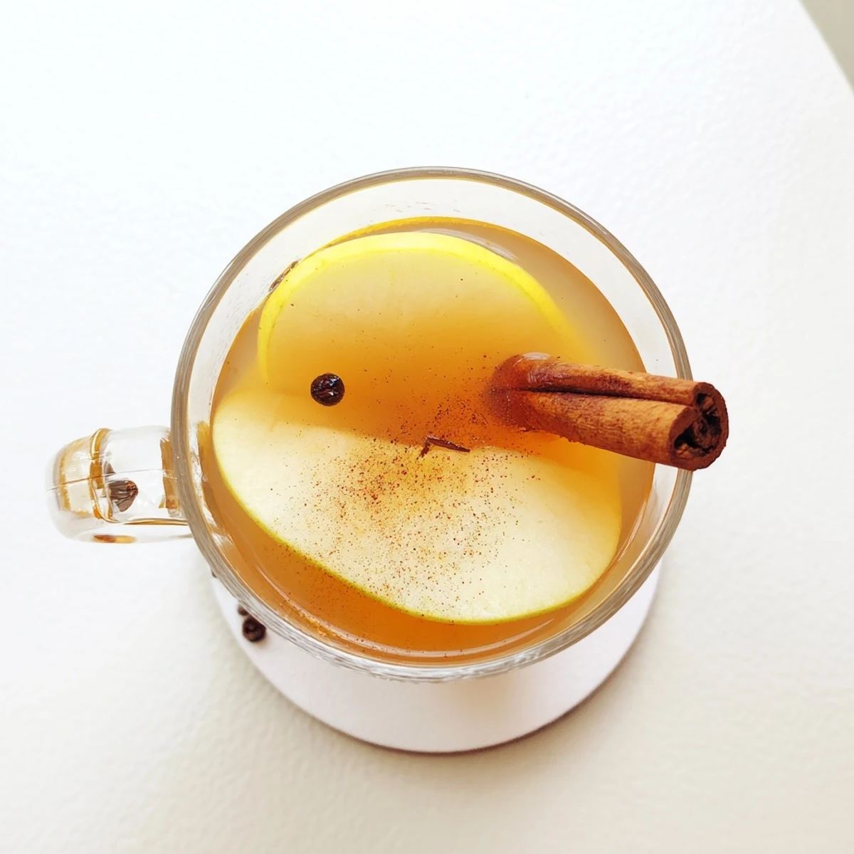 Steaming mug of cinnamon pear cider garnished with fresh pear slices and cinnamon stick