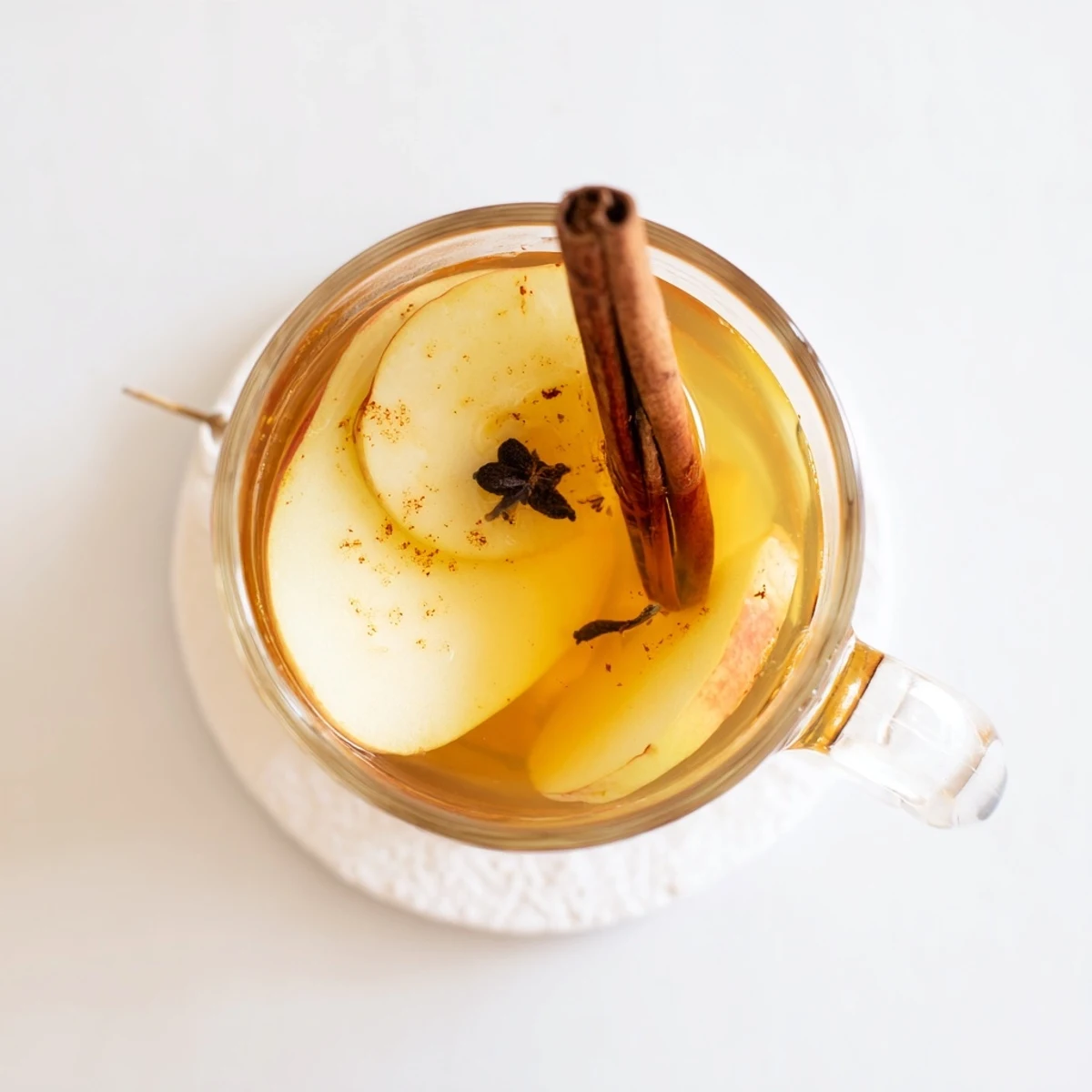 Rustic pitcher of spiced cinnamon pear cider surrounded by whole pears and cinnamon sticks