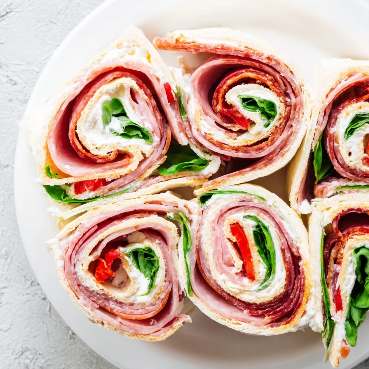 Colorful tortilla pinwheels stuffed with roasted red peppers, spinach, and savory Italian deli meats