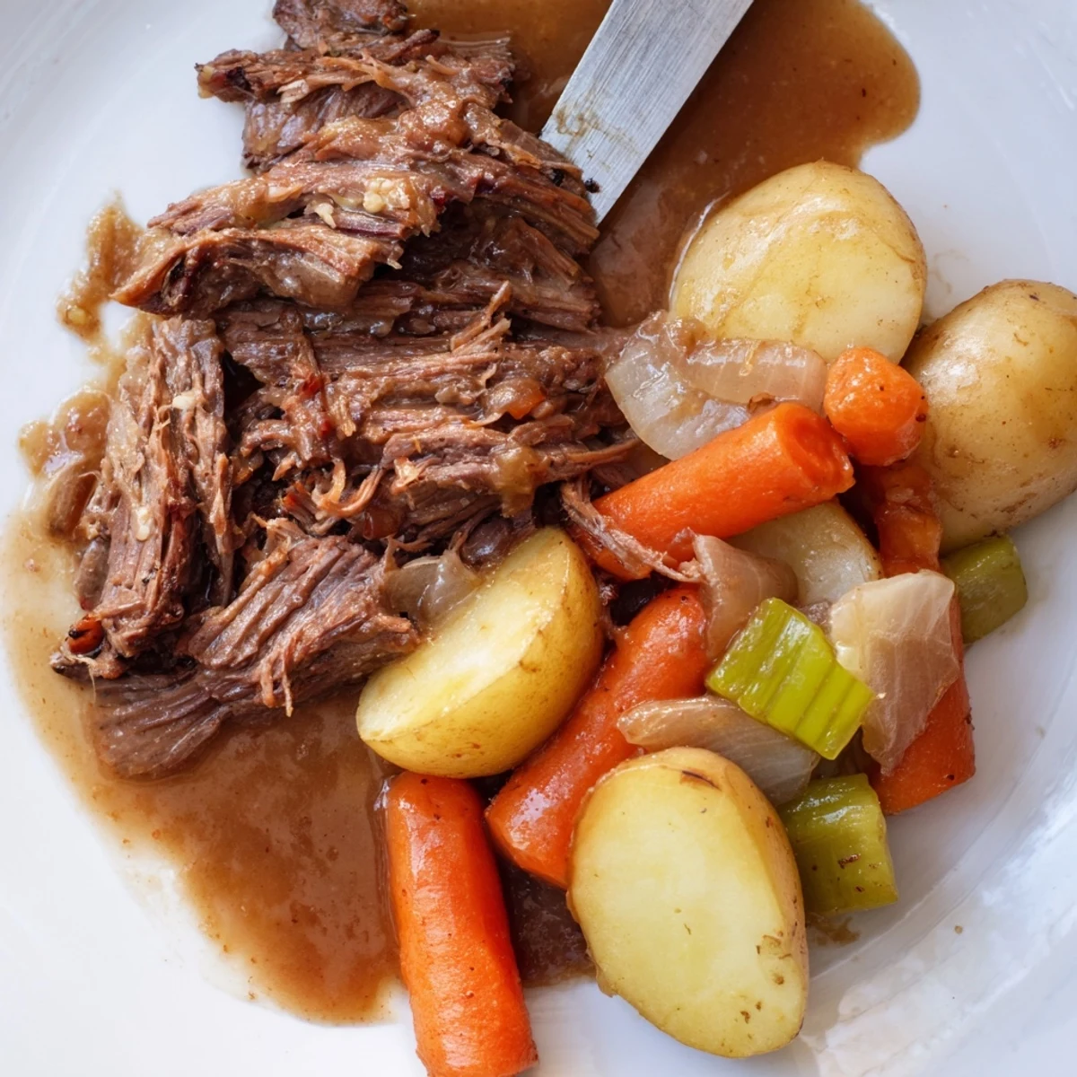 Golden brown Southern style pot roast served with tender carrots, potatoes, and rich brown gravy