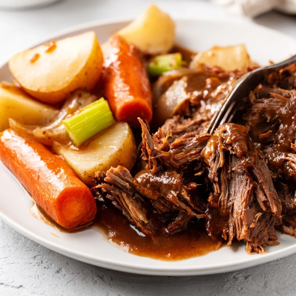 Slow-cooked Southern style pot roast plated with chunky vegetables and drizzled with thick homemade gravy