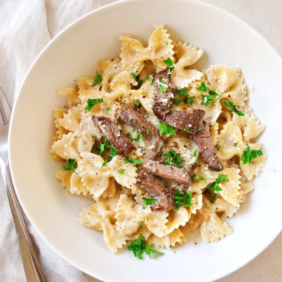 Tender bowtie pasta coated in zesty Cajun Alfredo sauce topped with seasoned beef slices