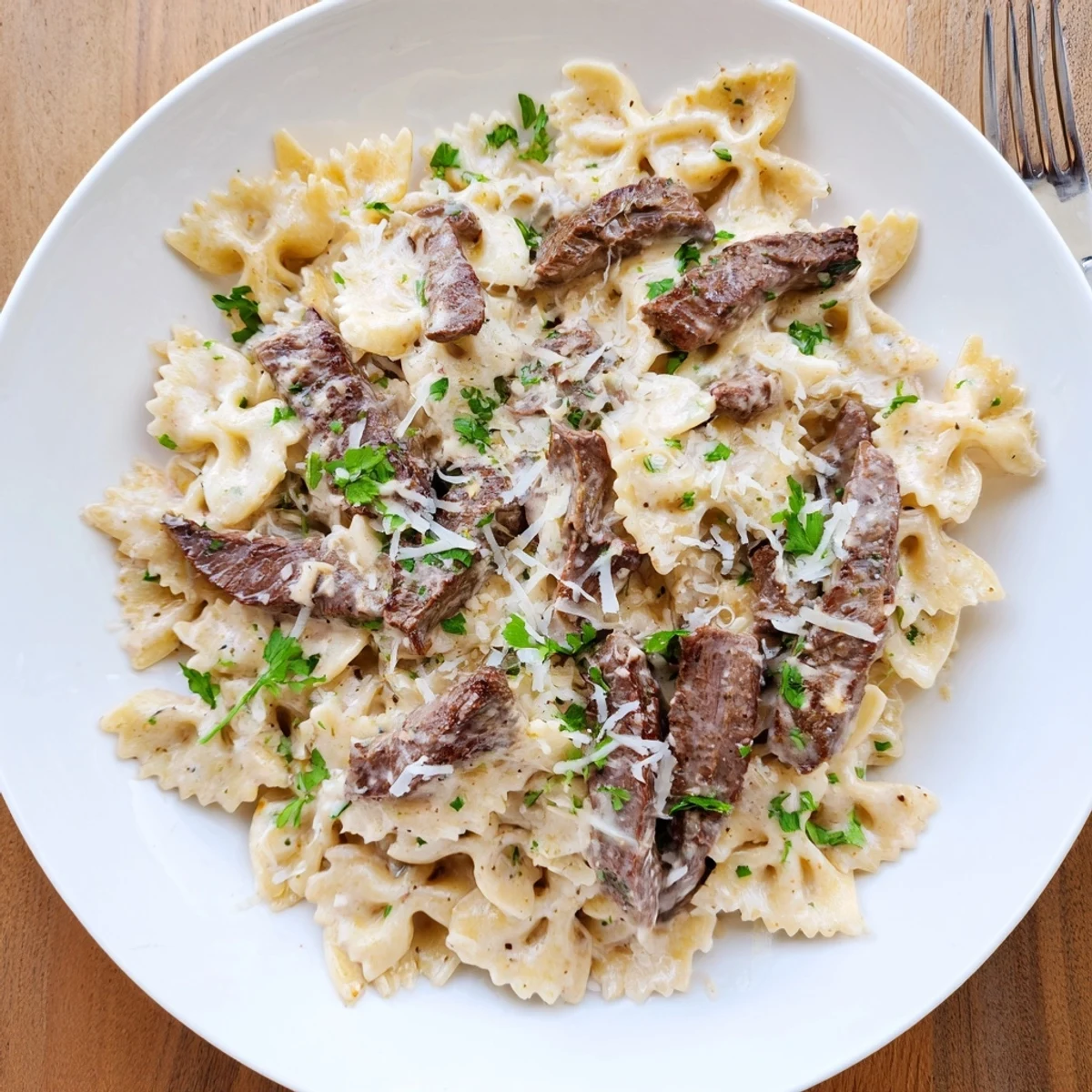 Creamy Cajun Alfredo pasta with spiced beef garnish sprinkled with fresh parsley and Parmesan