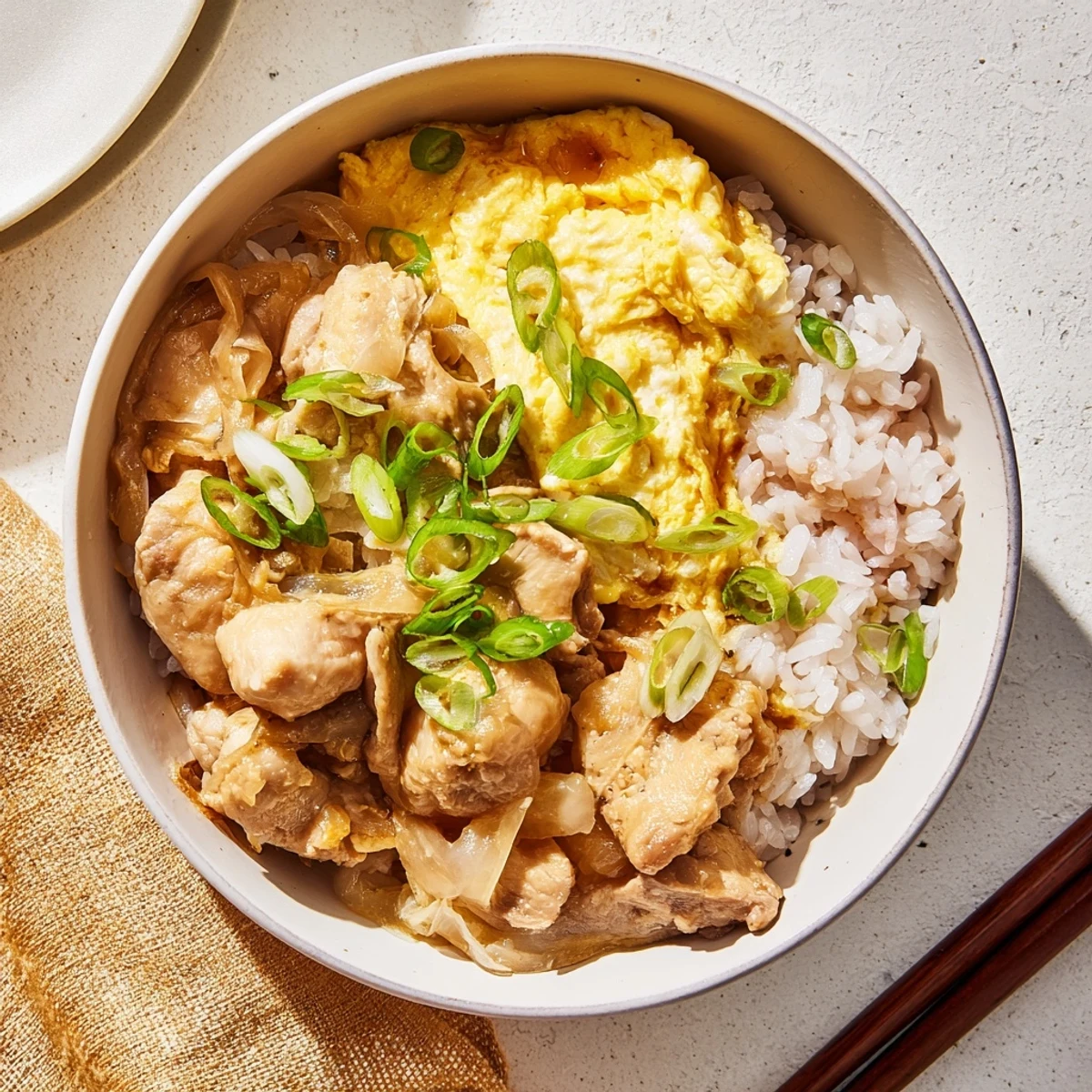 Comforting oyakodon served in a deep bowl with silky egg topping and green onion garnish