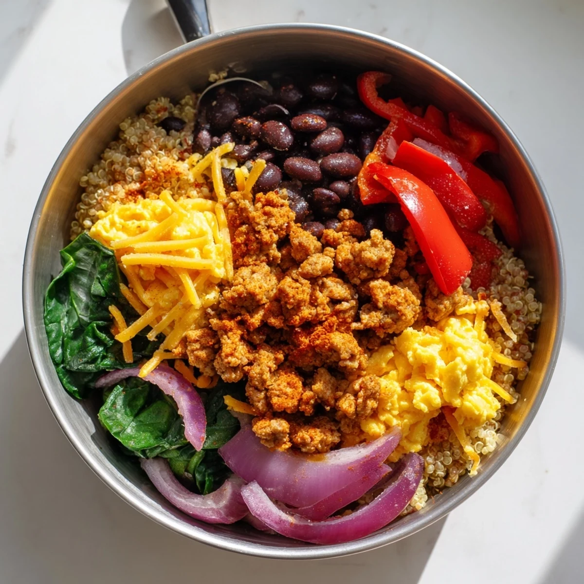 Colorful meal prep container filled with high protein freezer friendly breakfast bowls featuring fluffy scrambled eggs, savory turkey sausage, black beans, and quinoa topped with shredded cheddar cheese and fresh vegetables