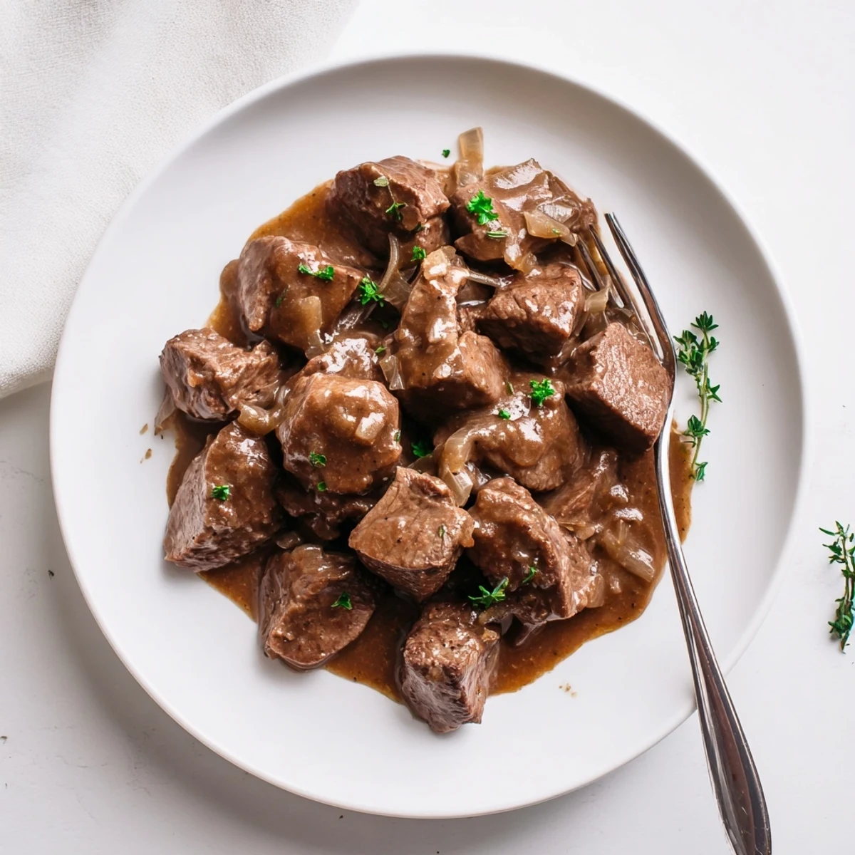 Slow cooker beef tips and gravy served over creamy mashed potatoes with fresh parsley garnish