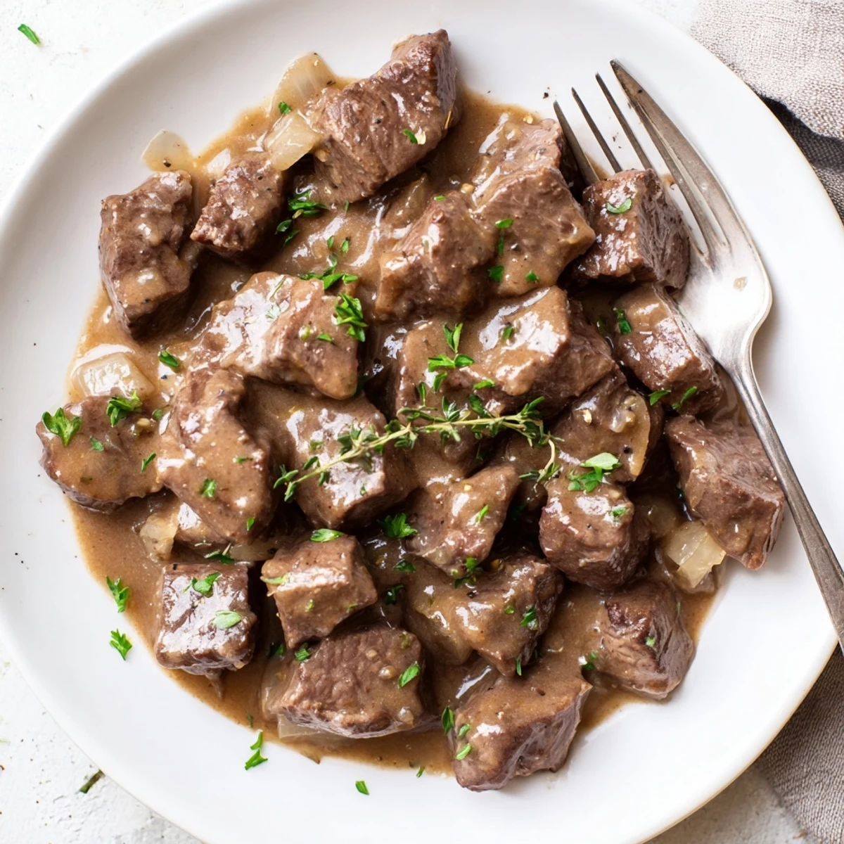 Tender beef tips in rich savory gravy plated alongside buttered egg noodles for a comforting dinner