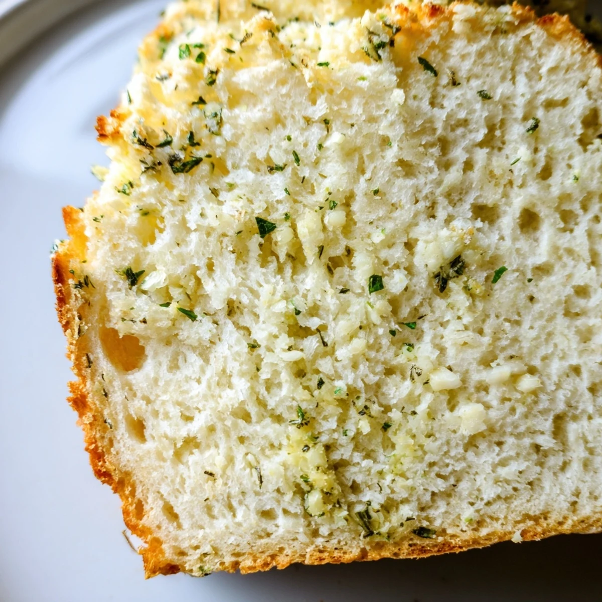 Fluffy homemade garlic and herb bread brushed with butter and fresh chopped herbs