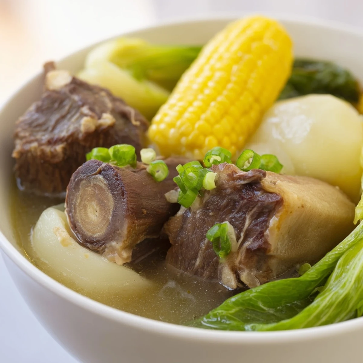 Steaming bowl of Filipino Bulalo featuring tender beef shank and golden bone marrow