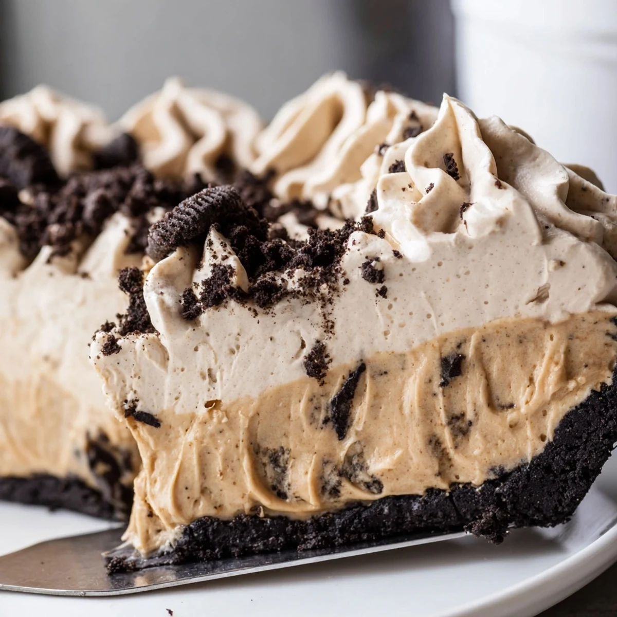 Creamy peanut butter Oreo pie sliced thick with fluffy whipped cream and cookie crumbles