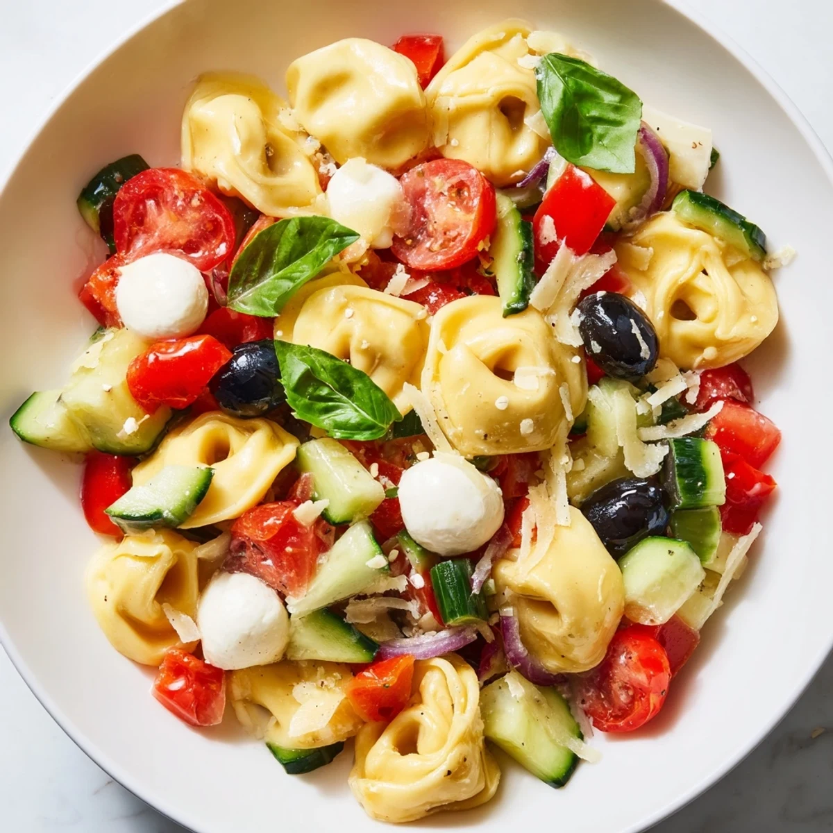Colorful tortellini salad tossed with cherry tomatoes, cucumber, and zesty Italian dressing in a rustic bowl