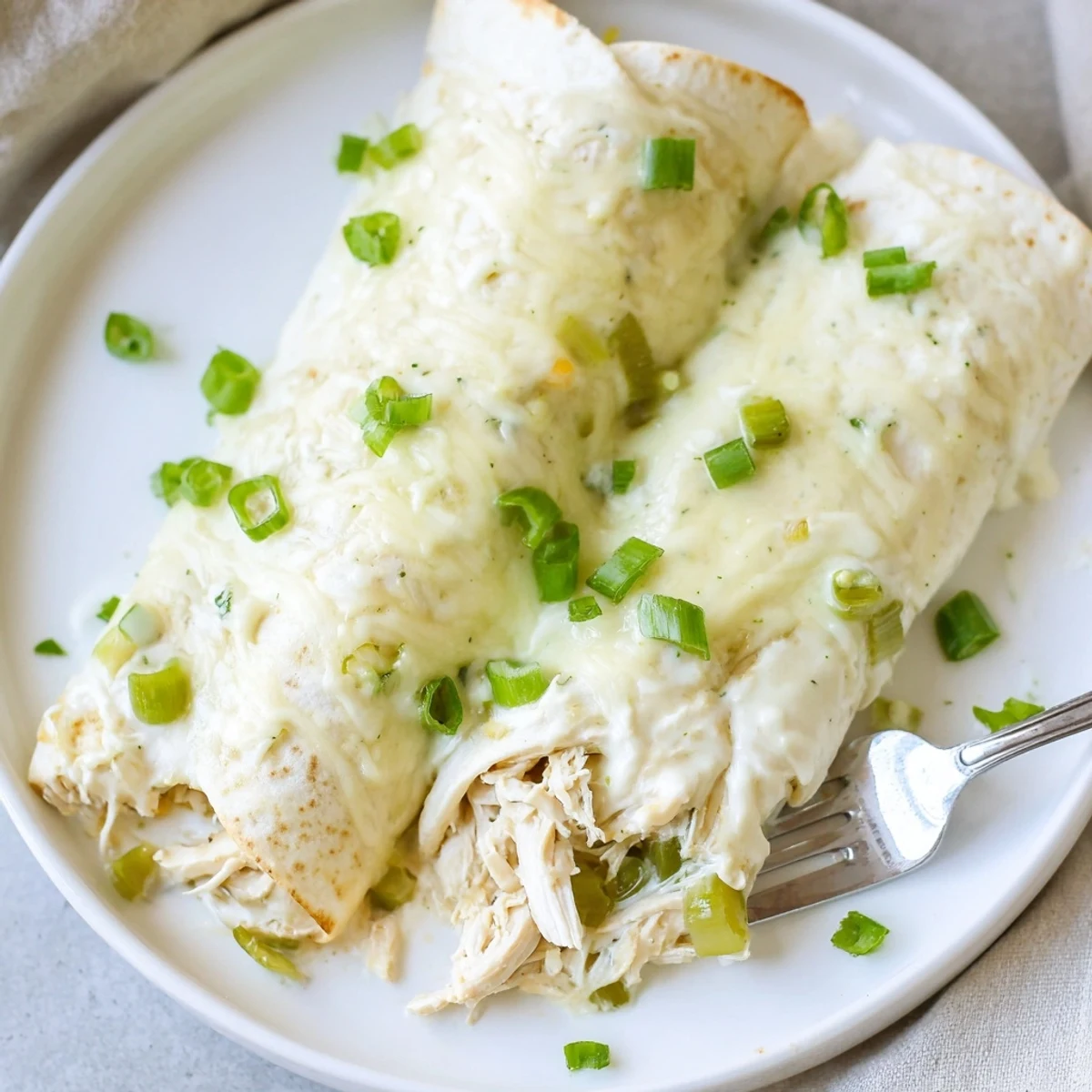 In a 9x13 pan, golden Creamy White Chicken Enchiladas, bubbly and garnished