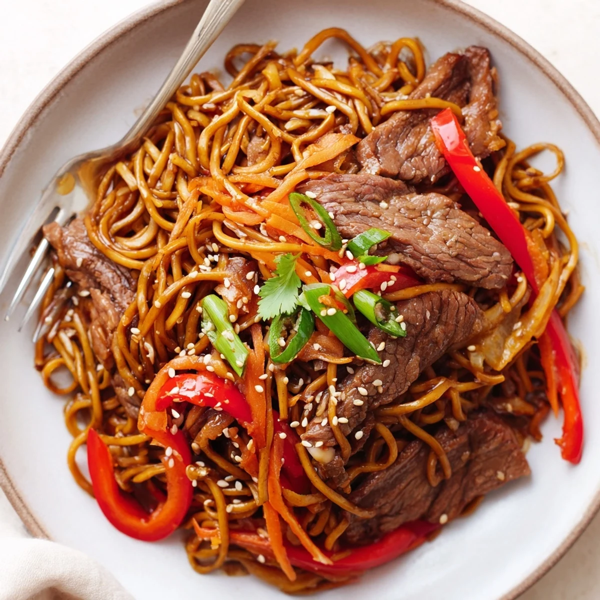 Sticky Beef Noodles glistening with glossy sauce, tender strips and vegetables
