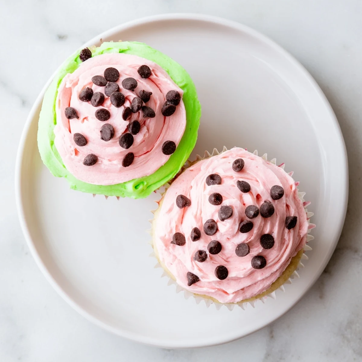 Fluffy pink watermelon cupcakes decorated to look like fresh sliced watermelon on summer dessert table