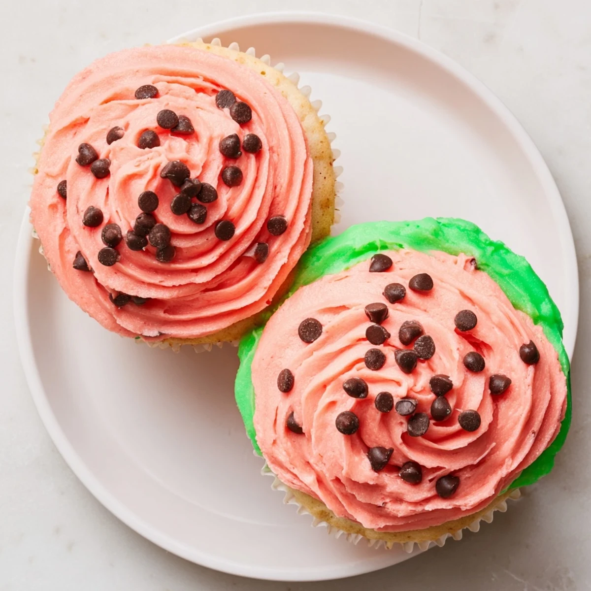 Freshly baked watermelon cupcakes arranged on a white serving platter with green rind detail