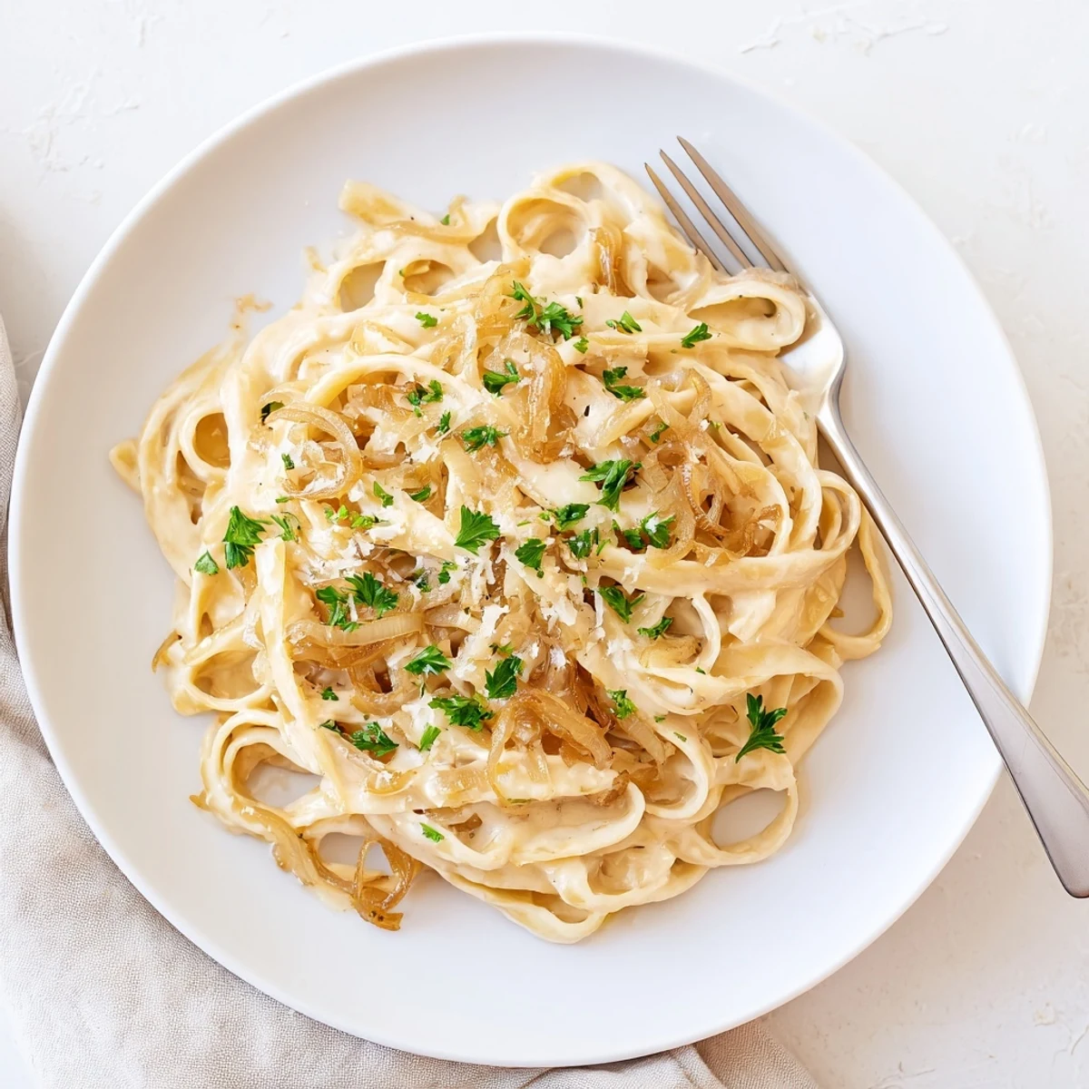 Creamy caramelized onion pasta dish garnished with fresh parsley and parmesan