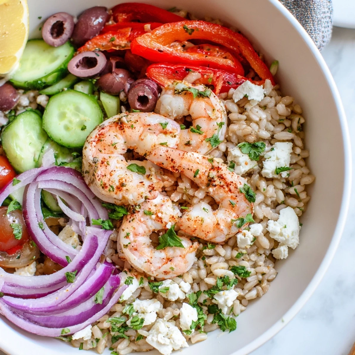 Colorful Greek Shrimp Mediterranean Bowl topped with olives, roasted peppers, and zesty lemon dressing