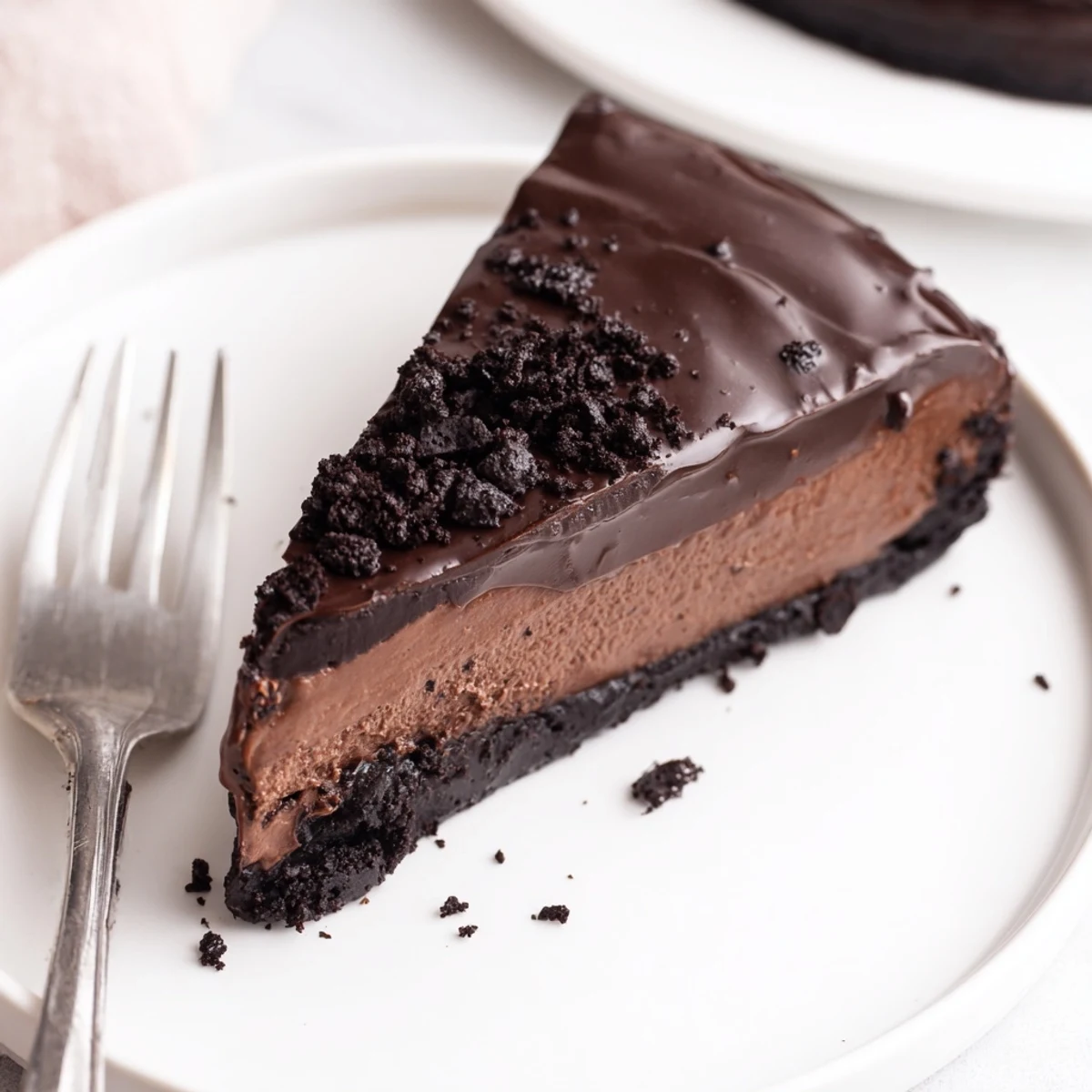 Homemade Oreo chocolate cheesecake with whipped chocolate ganache and halved cookies on a serving platter.