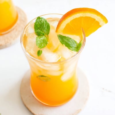 A pitcher holds the tropical blend garnished with orange slices and fresh mint leaves for a vibrant, hydrating beverage.  